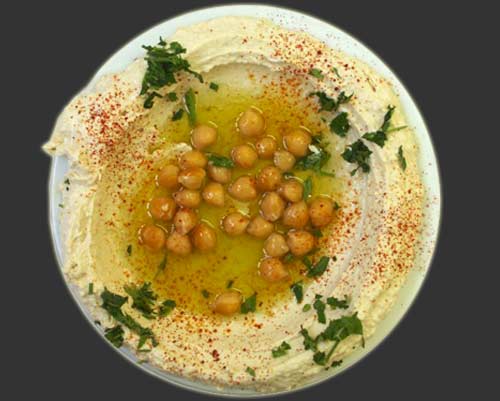 plate of hummus with chickpeas, black background